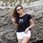 mujer apoyada en una roca con un short blanco y una camiseta negra