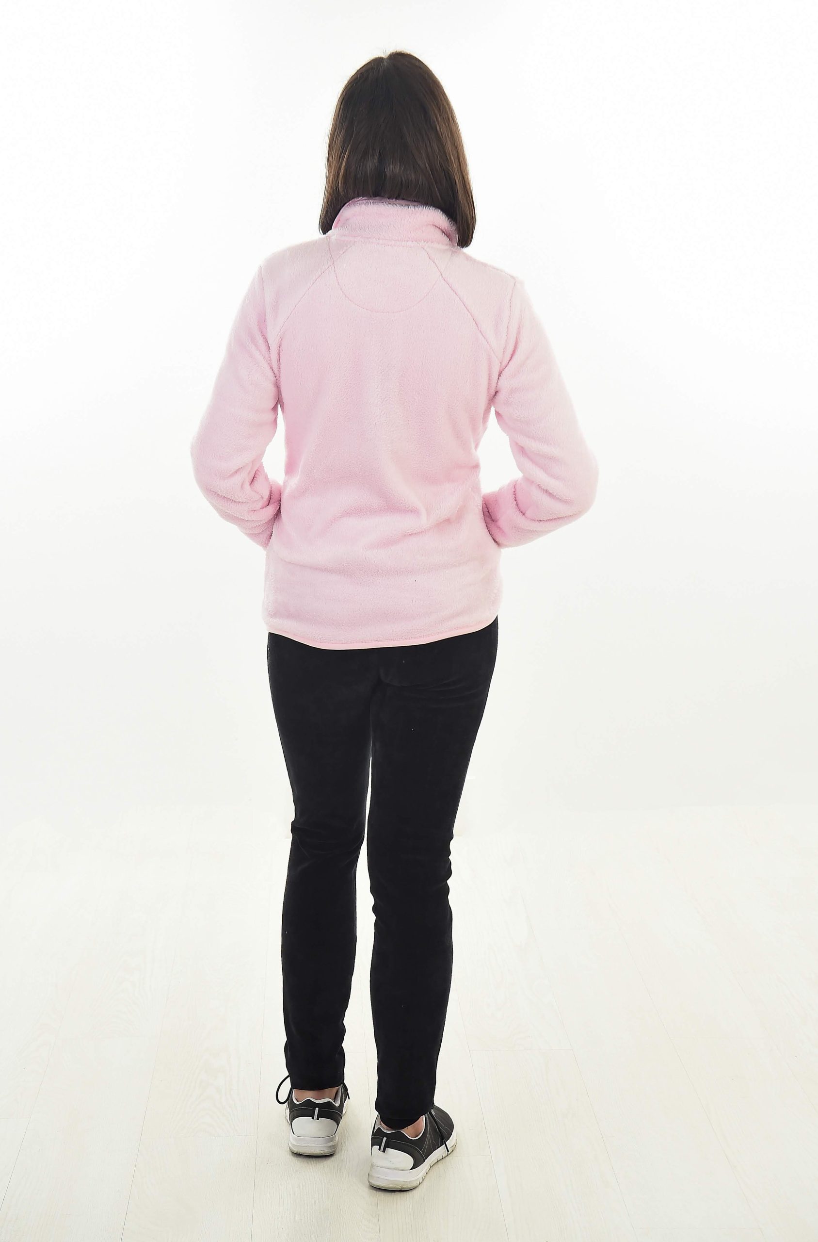 MUJER EN FONDO BLANCO CON UN PANTALON NEGRO Y UNA CHAQUETA ROSA PALO DE TEJIDO PELUCHE