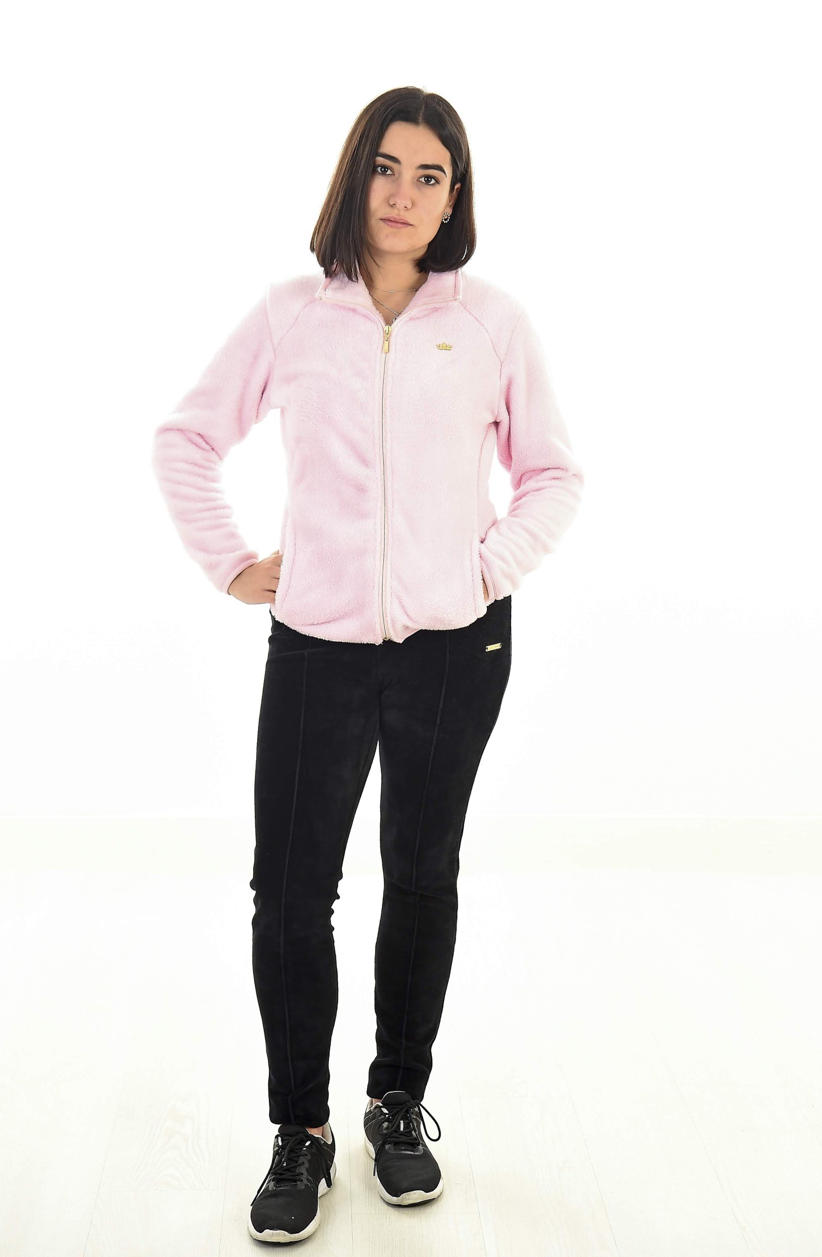 MUJER EN FONDO BLANCO CON UN PANTALON NEGRO Y UNA CHAQUETA ROSA PALO DE TEJIDO PELUCHE