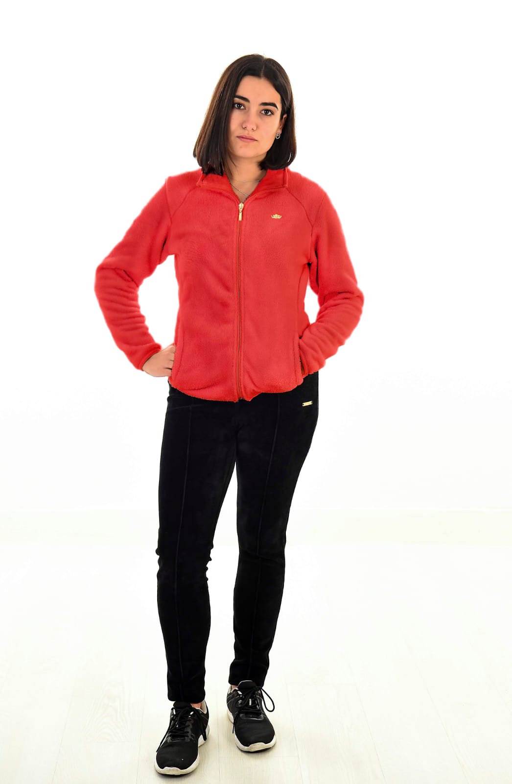 MUJER EN FONDO BLANCO CON UN PANTALON NEGRO Y UNA CHAQUETA ROJA DE TEJIDO PELUCHE
