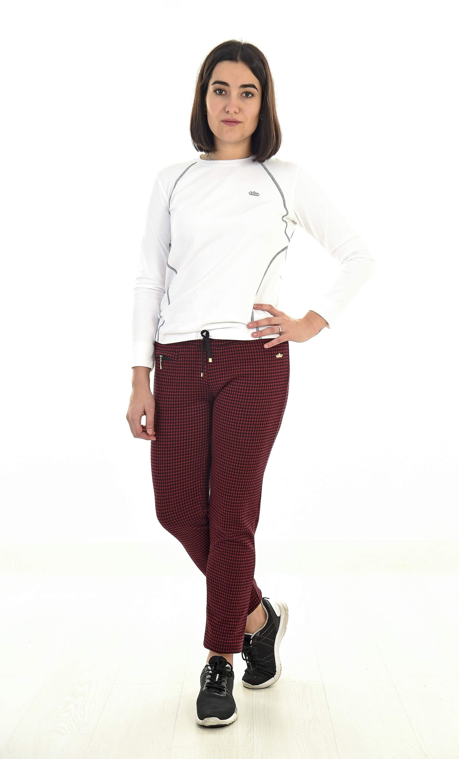 MUJER EN FONDO BLANCO CON UN PANTALON DE CUADROS NEGRO Y ROJO Y UN POLAR BLANCO CON PESPUNTES NEGROS