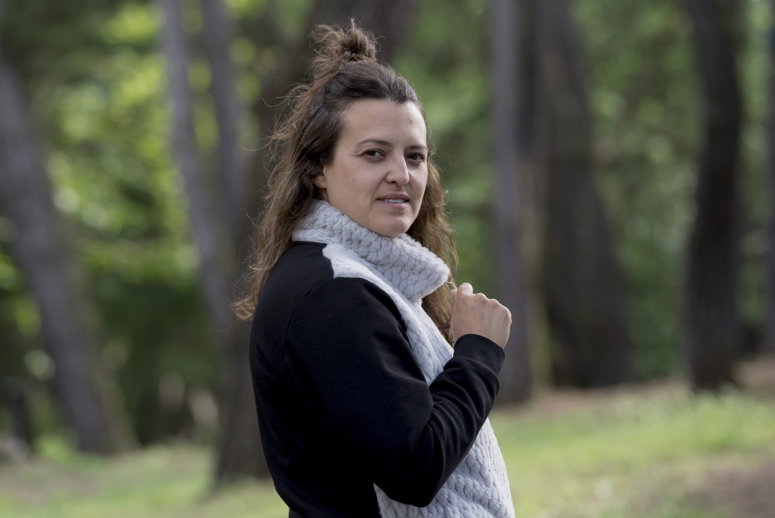 Mujer con chaqueta de pelo negra y gris en bosque