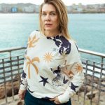 chica en una barandilla con el mar de fondo y nuestra sudadera sirena con un estampado super veraniego